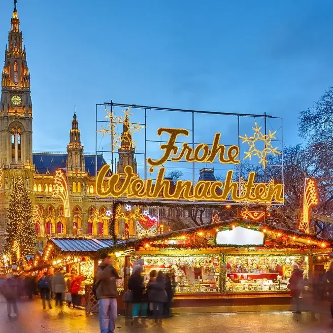 German Christmas market scene with festive lights, decorations, and a historic building in the background.